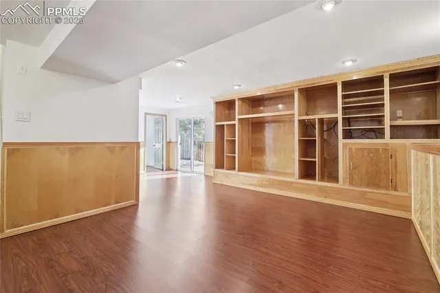 a view of an empty room with wooden floor and windows