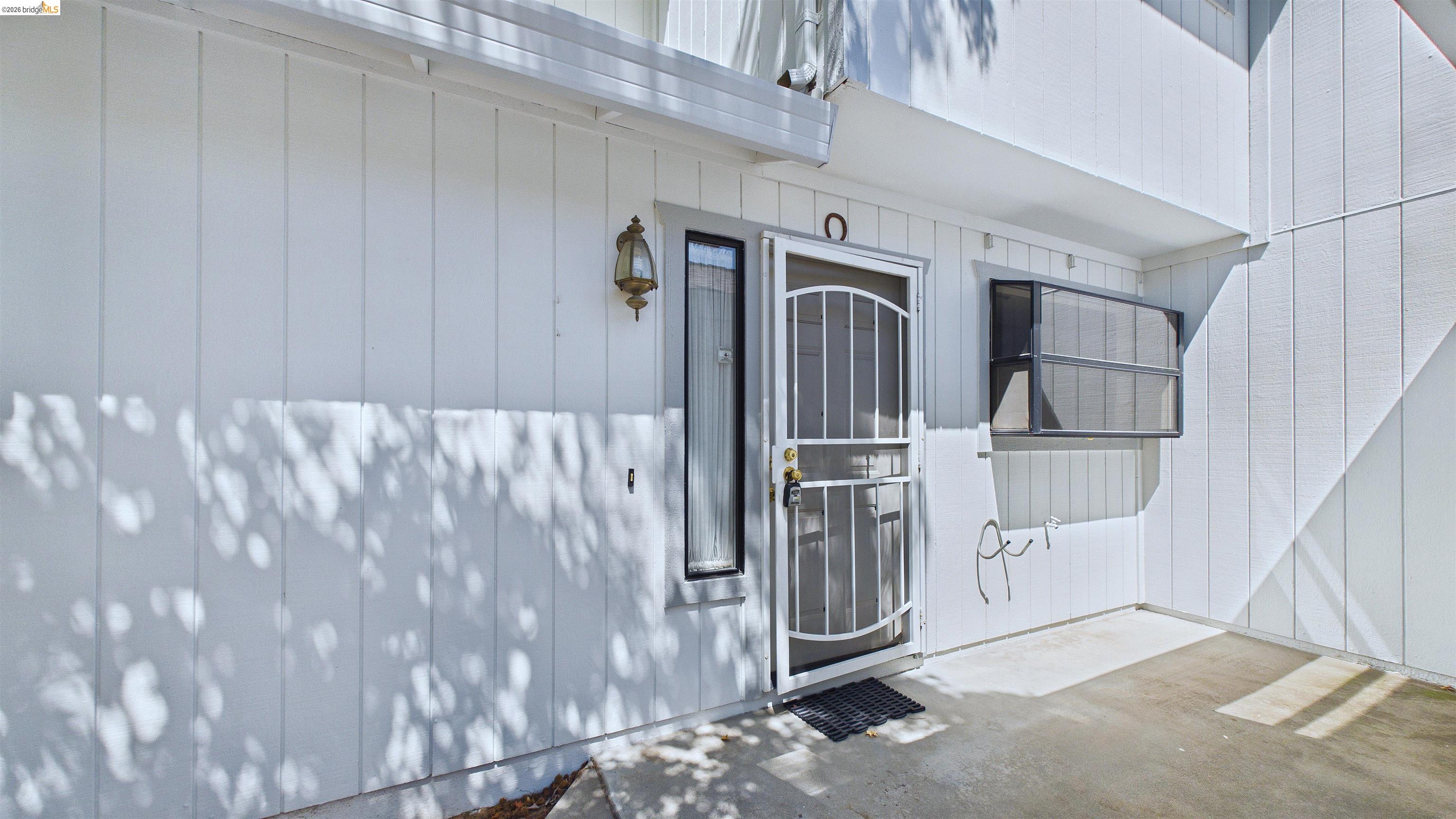 23686 Marble Quarry Road, Unit 72 Columbia, CA 95310 - Photo 2 of 35 Vertical white siding exterior with a screen door entry, an exterior light fixture, and a window with a security screen
