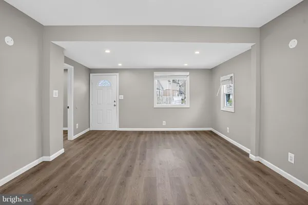 a view of an empty room with wooden floor and windows