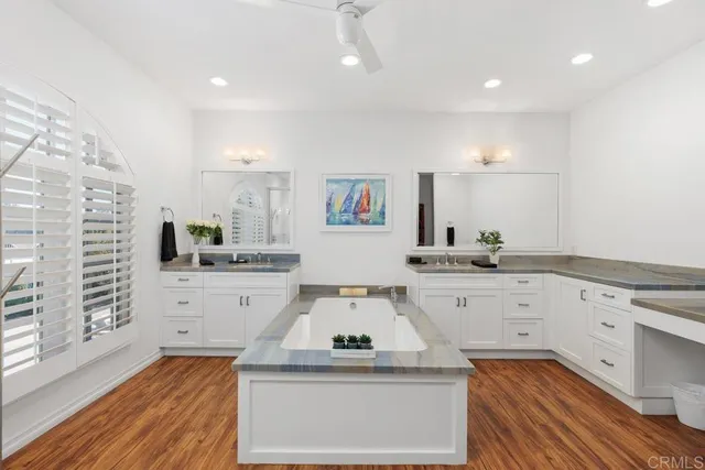 a view of center kitchen island a sink a wooden floor and white cabinets
