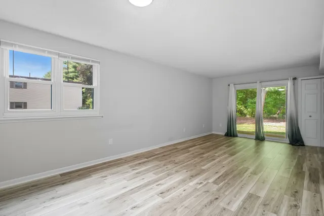 a view of an empty room with wooden floor and a window
