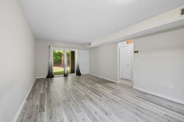 a view of empty room with wooden floor and window