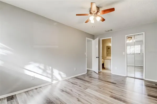 a view of empty room with wooden floor and fan
