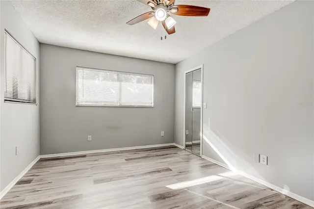 a view of empty room with wooden floor and fan