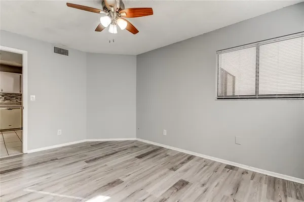 a view of empty room with wooden floor and fan