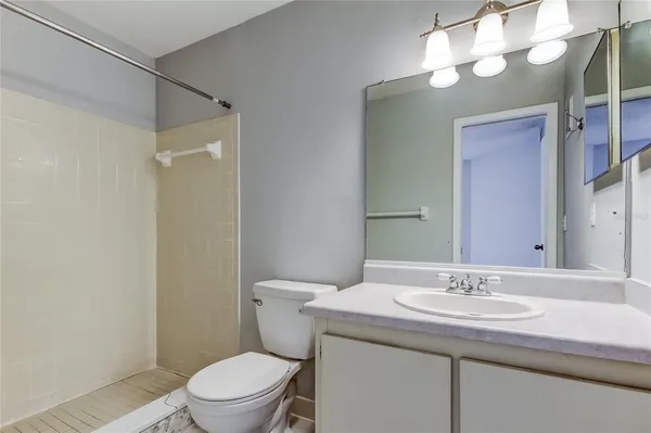 a bathroom with a sink a toilet a mirror and shower