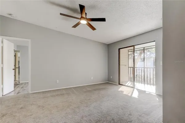 an empty room with a ceiling fan and window