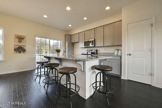 a kitchen with stainless steel appliances kitchen island granite countertop wooden floors and white cabinets