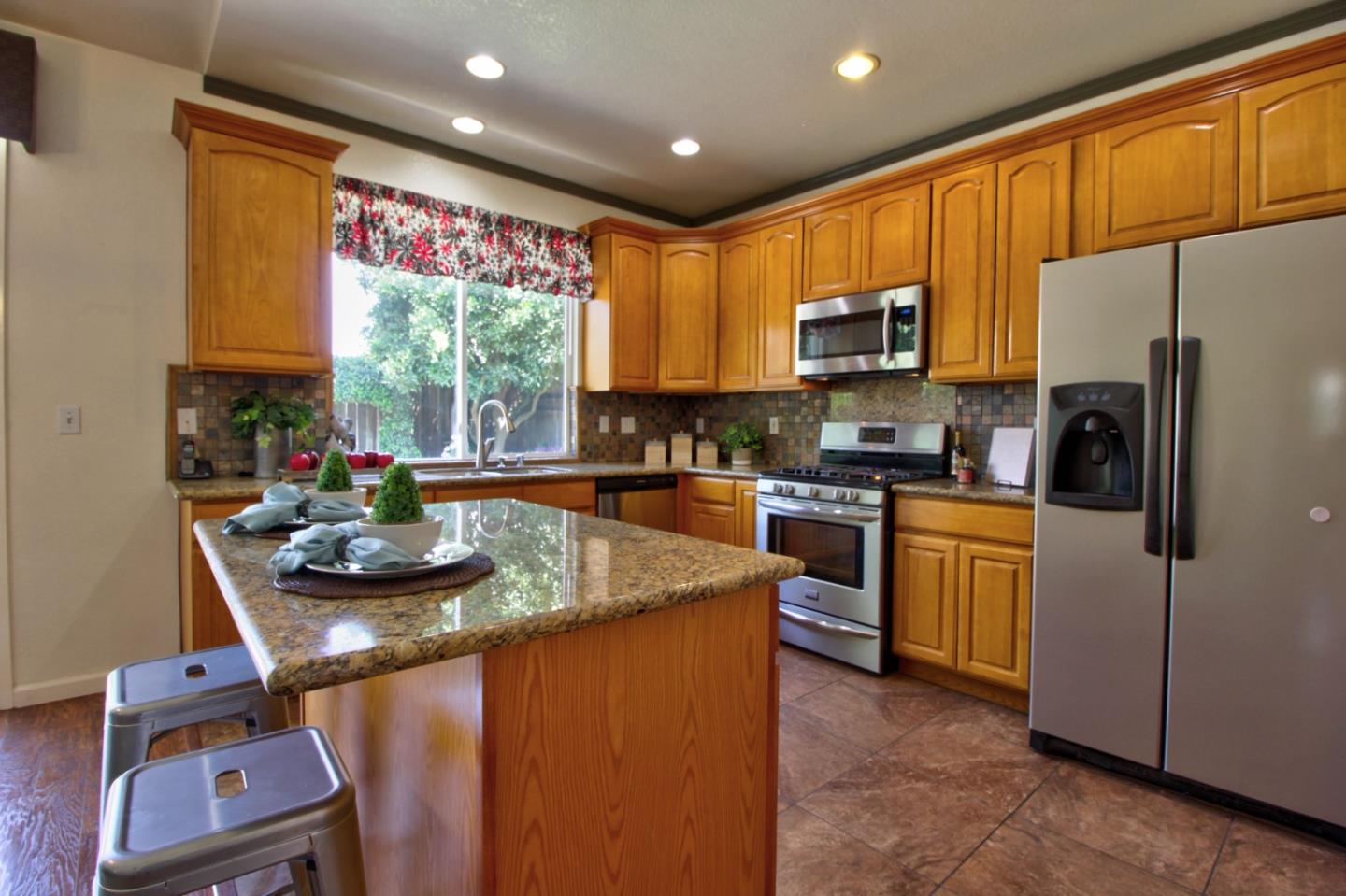 1833 Rail Street Manteca, CA 95337 - Photo 14 of 33 a kitchen with kitchen island granite countertop stainless steel appliances a stove a sink a refrigerator cabinets and a dining table
