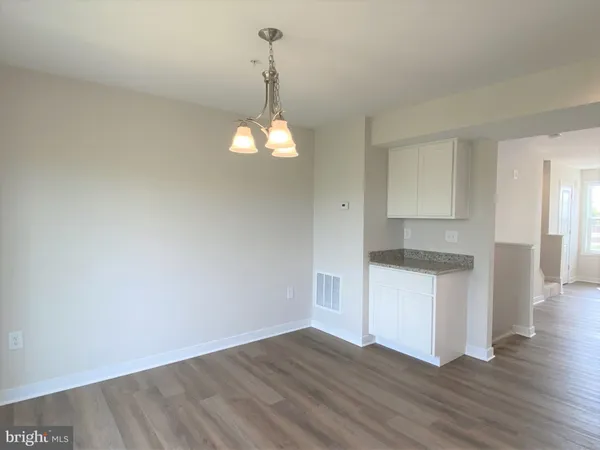 a kitchen with granite countertop white cabinets and a wooden floor