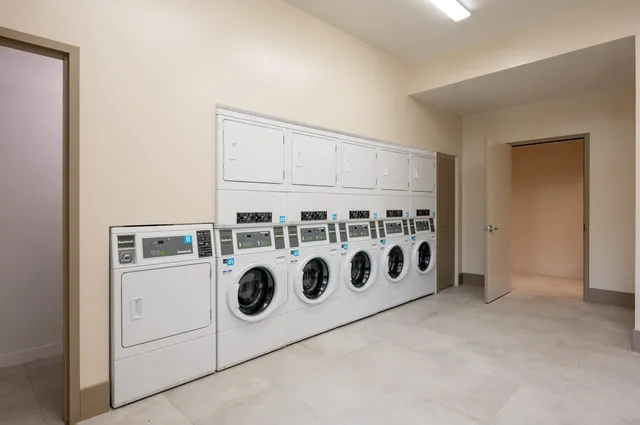 a utility room with stainless steel appliances wooden cabinets washer and dryer