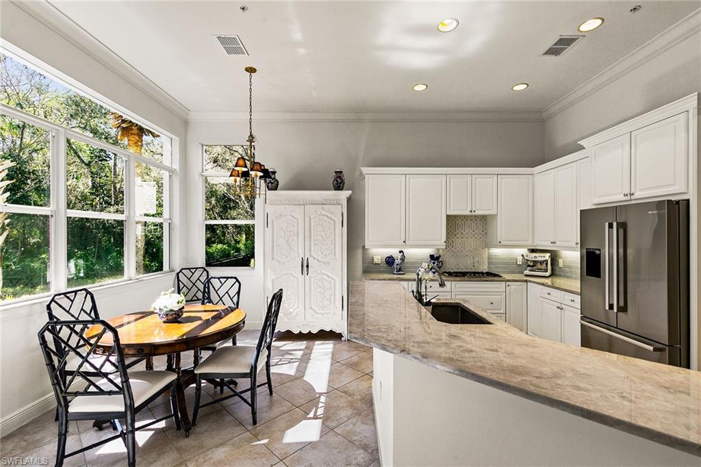 28540 Calabria Court, Unit 102 Naples, FL 34110 - Photo 16 of 32 a kitchen with refrigerator a stove and chairs