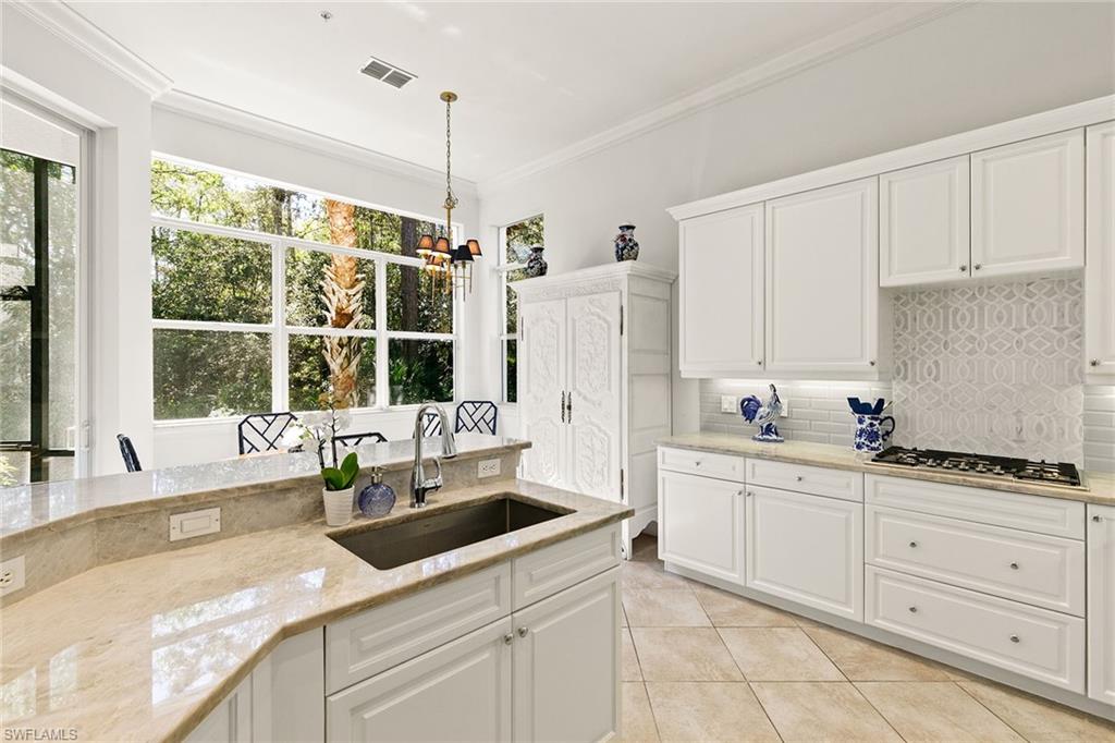 28540 Calabria Court, Unit 102 Naples, FL 34110 - Photo 19 of 32 a kitchen with white cabinets and window