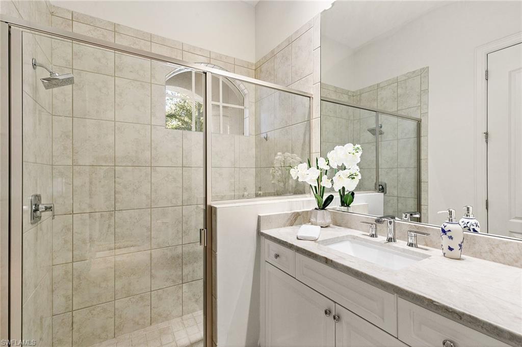 28540 Calabria Court, Unit 102 Naples, FL 34110 - Photo 27 of 32 a bathroom with a double vanity sink and shower