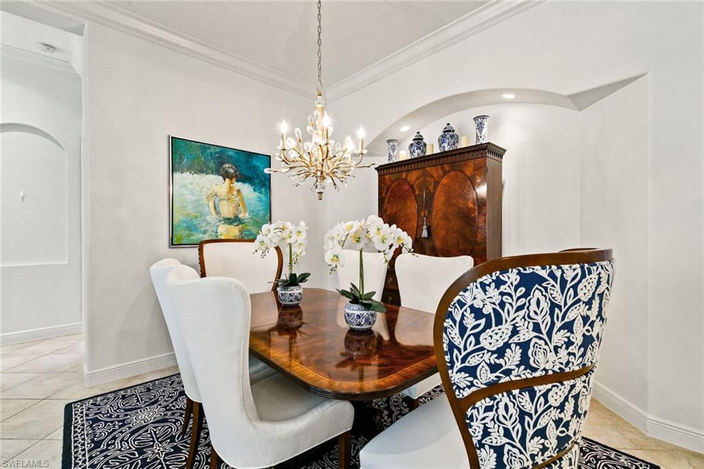 28540 Calabria Court, Unit 102 Naples, FL 34110 - Photo 3 of 32 a dining room with furniture a chandelier and wooden floor