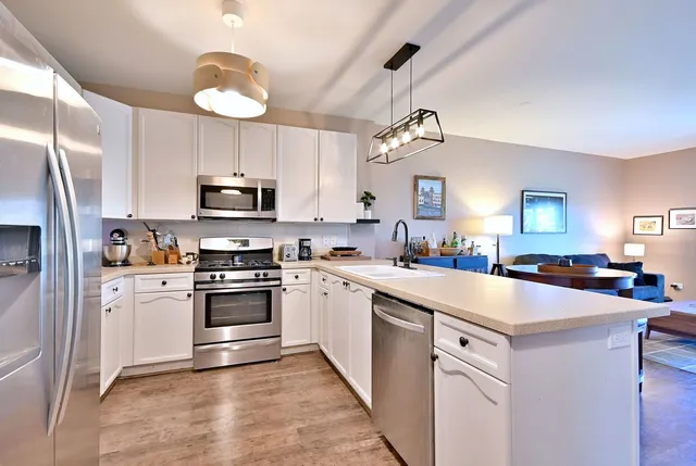 a kitchen with kitchen island granite countertop stainless steel appliances stove a sink and white cabinets