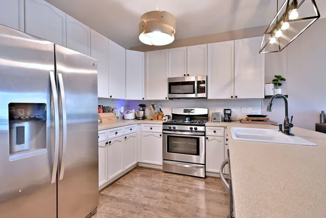 a large kitchen with stainless steel appliances a stove center island a refrigerator and cabinets