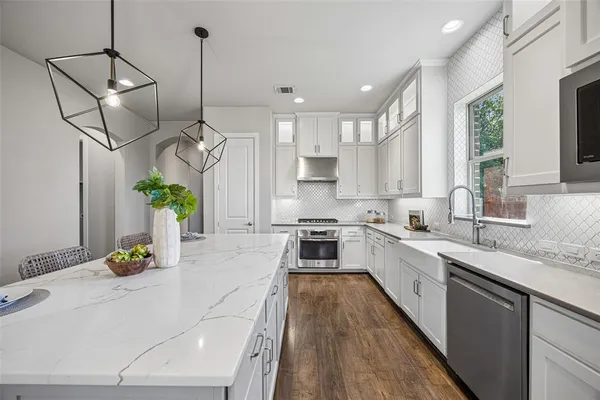 a kitchen with stainless steel appliances granite countertop a sink a stove and a wooden floors