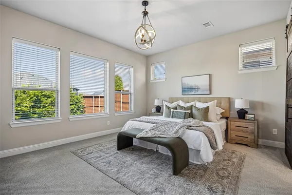 a spacious bedroom with a bed a dresser and next to a window