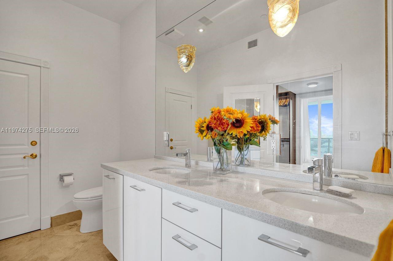 100 Lincoln Road, Unit PH12 Miami Beach, FL 33139 - Photo 26 of 59 a bathroom with a granite countertop sink a toilet and a mirror