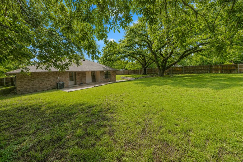 1001 Rosebud Drive Azle, TX 76020 - Photo 31 of 36 Expansive backyard featuring a manicured lawn, mature trees, and a wooden privacy fence