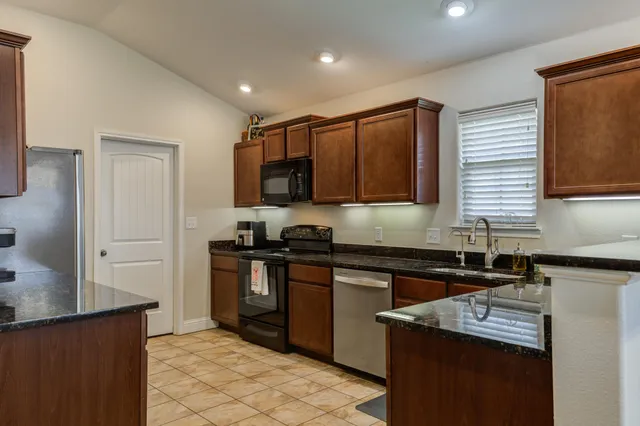 a kitchen with stainless steel appliances granite countertop a sink stove and refrigerator