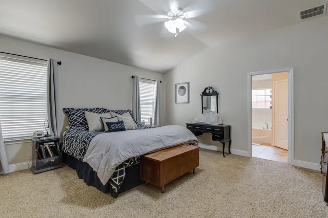a spacious bedroom with a bed a table and chair