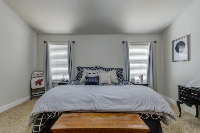 a bedroom with a bed two lamps and a large window