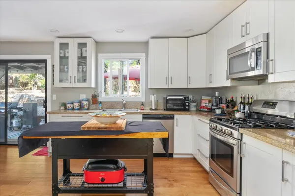 a kitchen with granite countertop a stove and white cabinets