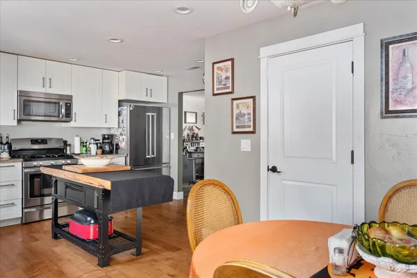 a kitchen with stainless steel appliances granite countertop a refrigerator a stove a sink a dining table and chairs with wooden floor