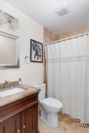 a bathroom with a granite countertop sink a toilet and a mirror