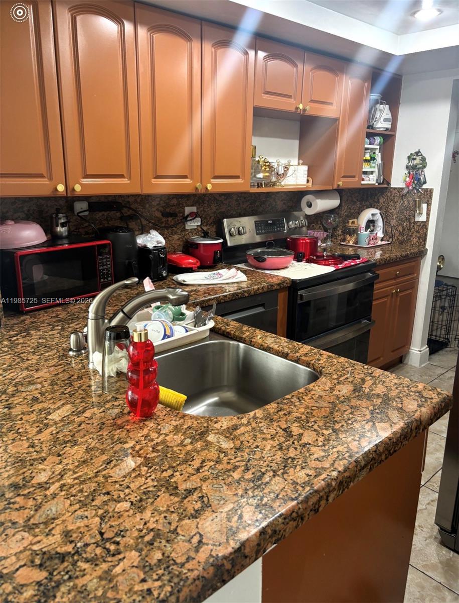 9441 Southwest 4th Street, Unit 111 Miami, FL 33174 - Photo 5 of 6 a kitchen with stainless steel appliances granite countertop a sink a stove and a microwave