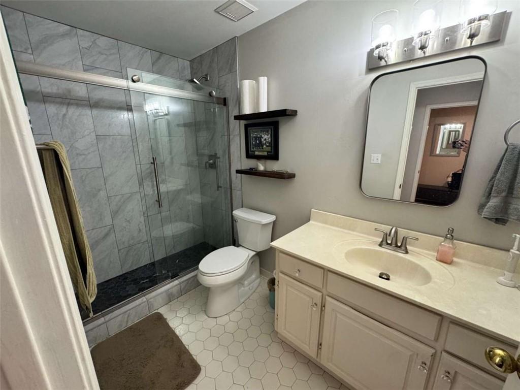 3201 Lenox Road Northeast, Unit 2 Atlanta, GA 30324 - Photo 23 of 39 a bathroom with a toilet a sink a glass door a shower and mirror