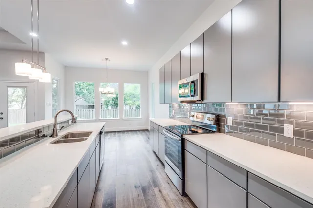 a kitchen with a sink a counter top space stainless steel appliances a window and a kitchen island