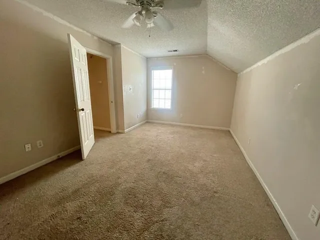 an empty room with a chandelier fan and windows