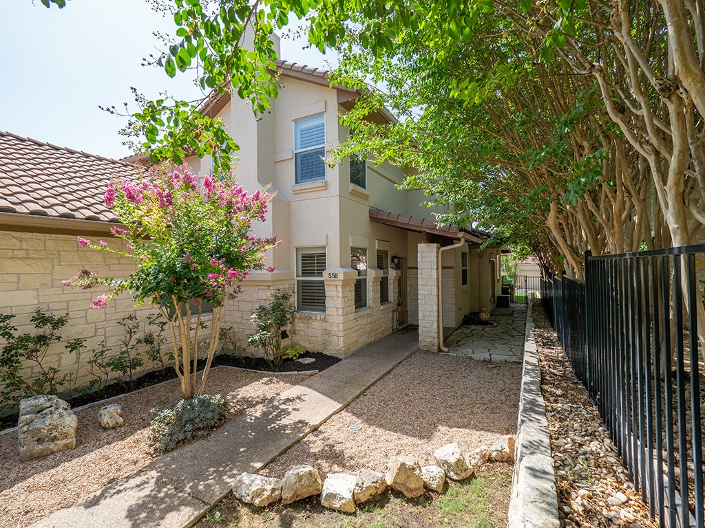 55 Tournament Way, Unit B The Hills, TX 78738 - Photo 3 of 23 Back of property with a tile roof, a fenced backyard, stucco siding, and stone siding