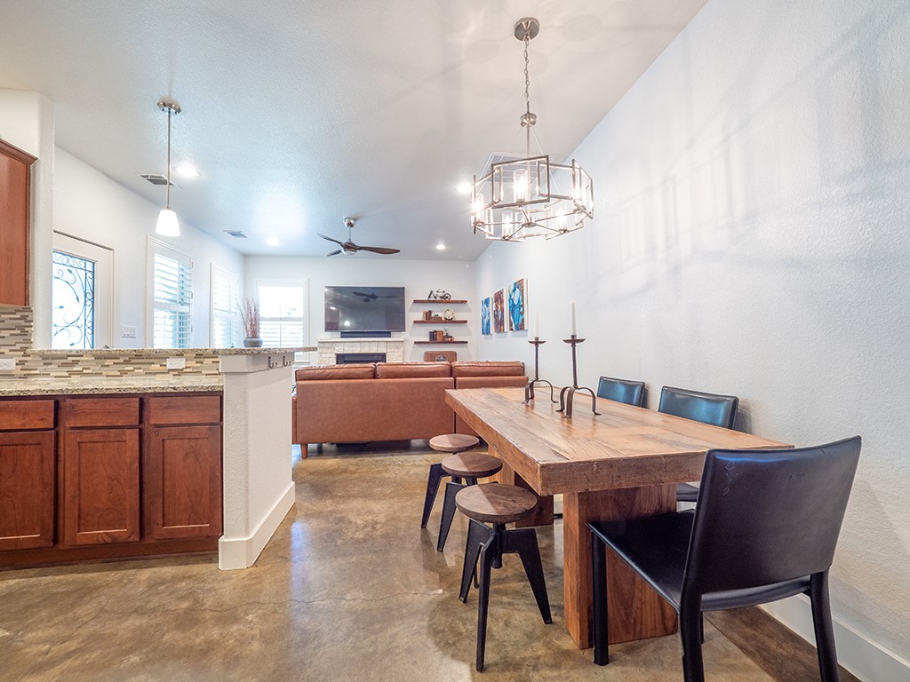 55 Tournament Way, Unit B The Hills, TX 78738 - Photo 10 of 23 Dining area with concrete floors, ceiling fan, a chandelier, a fireplace, and recessed lighting