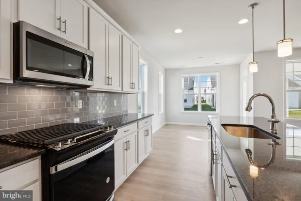 a kitchen with stainless steel appliances granite countertop a stove a microwave and a sink