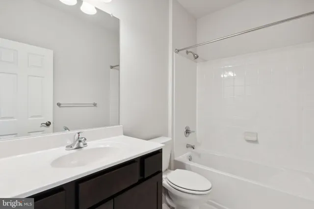 a bathroom with a bathtub shower sink vanity mirror and toilet