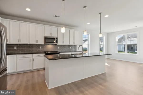 a large kitchen with granite countertop a stove a sink a center island and cabinets
