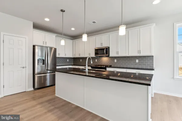 a kitchen with stainless steel appliances a refrigerator a stove a sink cabinets and a wooden floor