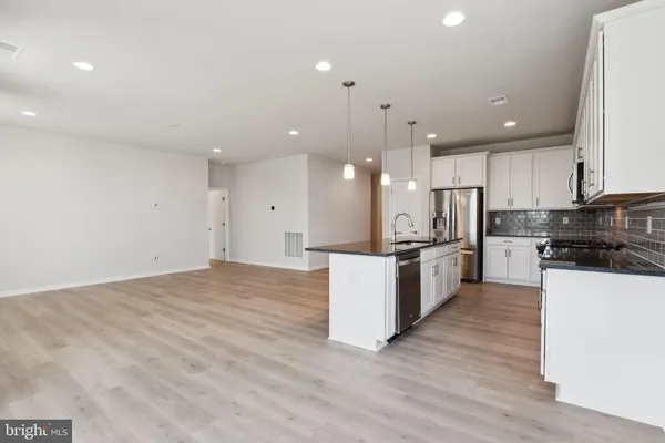 a large kitchen with stainless steel appliances kitchen island a large counter top and a stove top oven