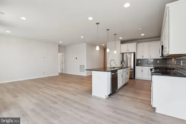 a large kitchen with stainless steel appliances kitchen island a large counter top and a stove top oven