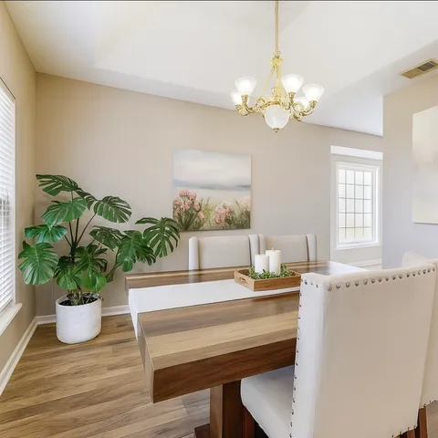 a dining room with chandelier and wooden floor