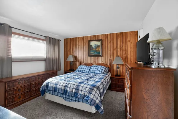 a bedroom with a bed a dresser and next to a window