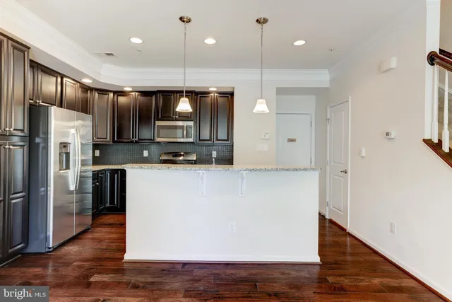a large kitchen with stainless steel appliances a refrigerator and a wooden floor