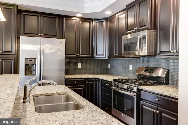 a kitchen with stainless steel appliances granite countertop a sink stove and refrigerator