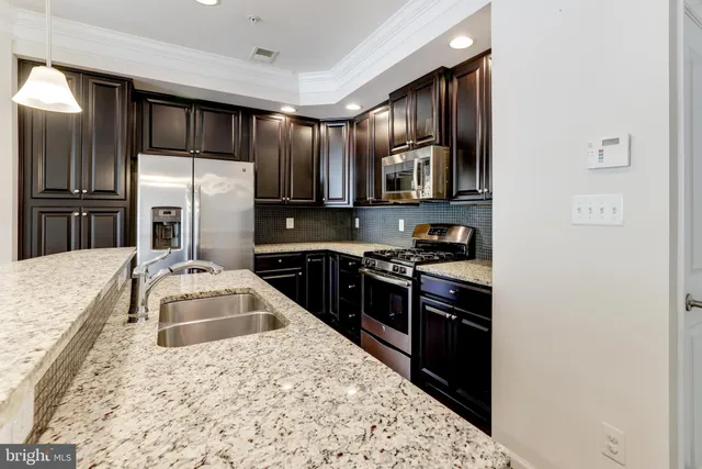 a kitchen with stainless steel appliances granite countertop a stove a sink and a refrigerator
