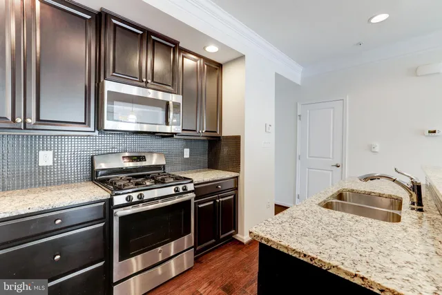 a kitchen with granite countertop cabinets stainless steel appliances and wooden floor