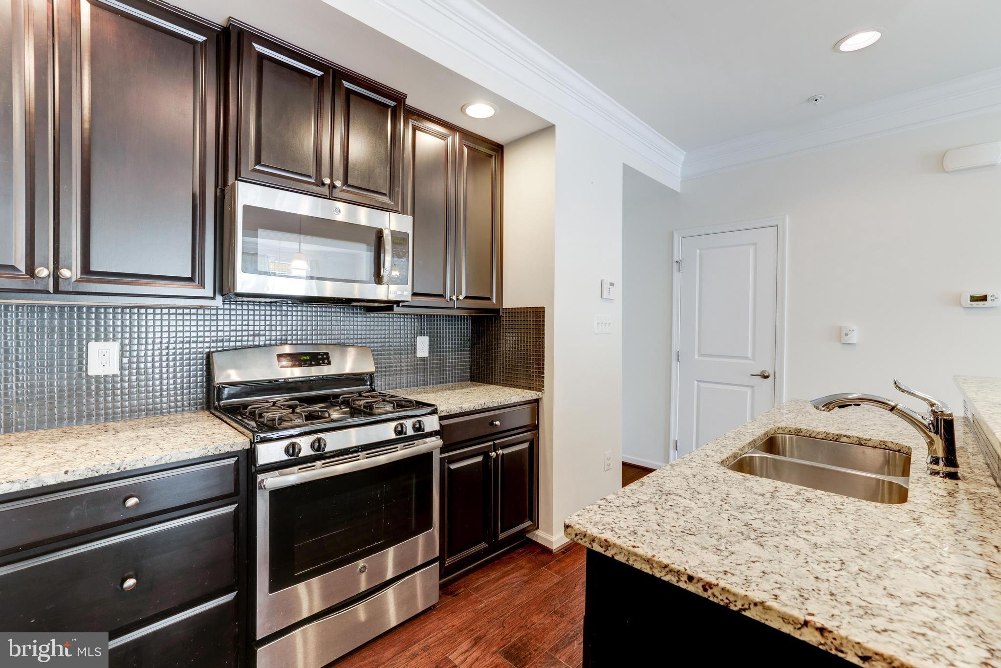 13643 Air And Parkway, Unit MUSEUM 9L Herndon, VA 20171 - Photo 22 of 45 a kitchen with granite countertop cabinets stainless steel appliances and wooden floor